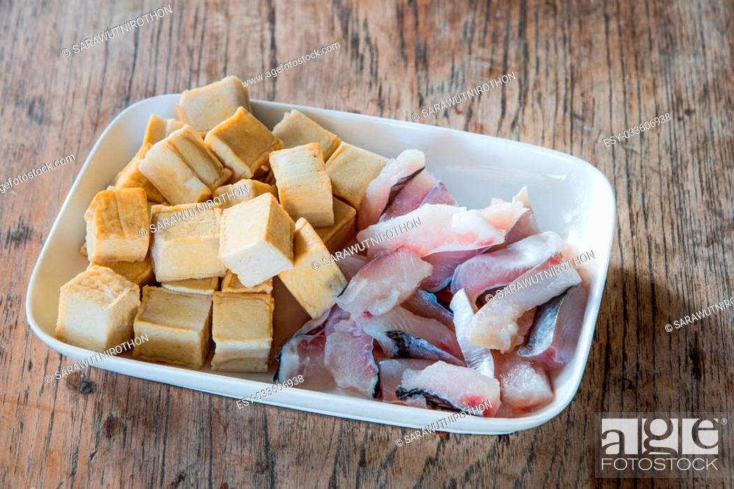 Stock Photo: Meat, fish and tofu dish in white placed on a wooden table. Focus on fish.