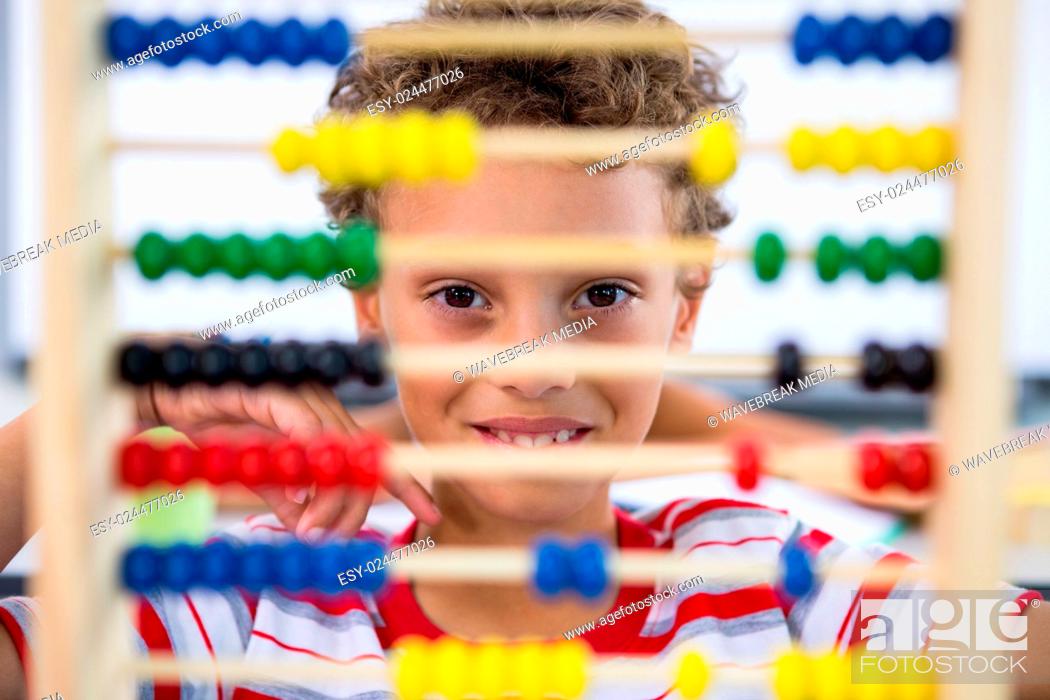 Stock Photo: Cute boy playing with abacus in classroom.