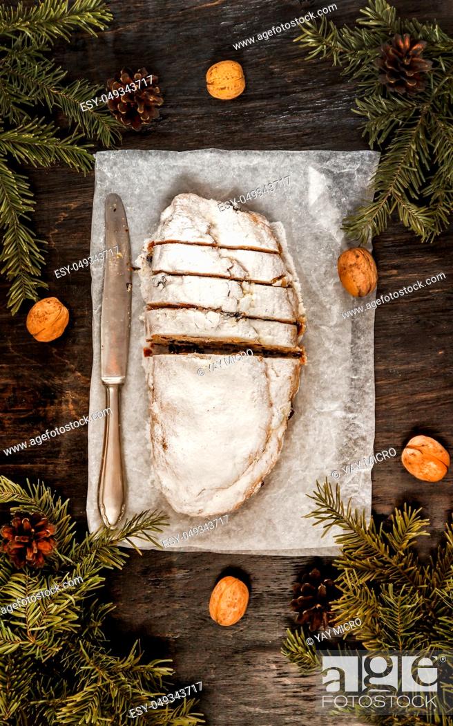 Stock Photo: Traditional German Christmas fruit cake stollen on a dark background, around the fir branches and walnuts. View from above, copy space, flat lay.