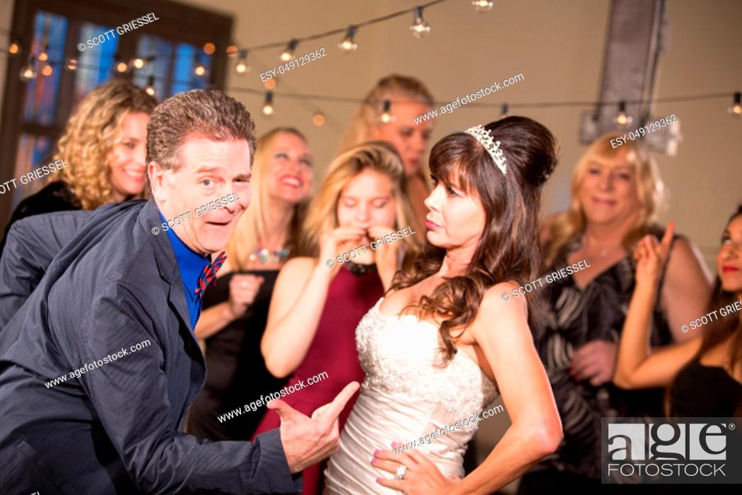 Stock Photo: Bride Glares at Man Doing Funny Dance at a Wedding.