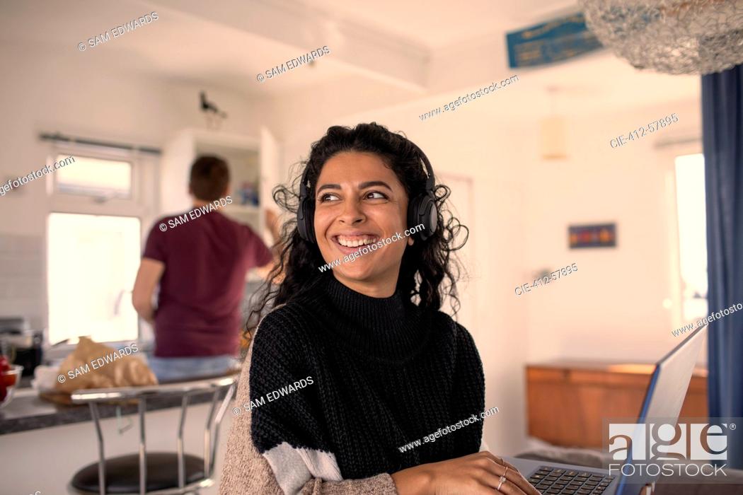 Photo de stock: Happy woman with headphones working from home at laptop.