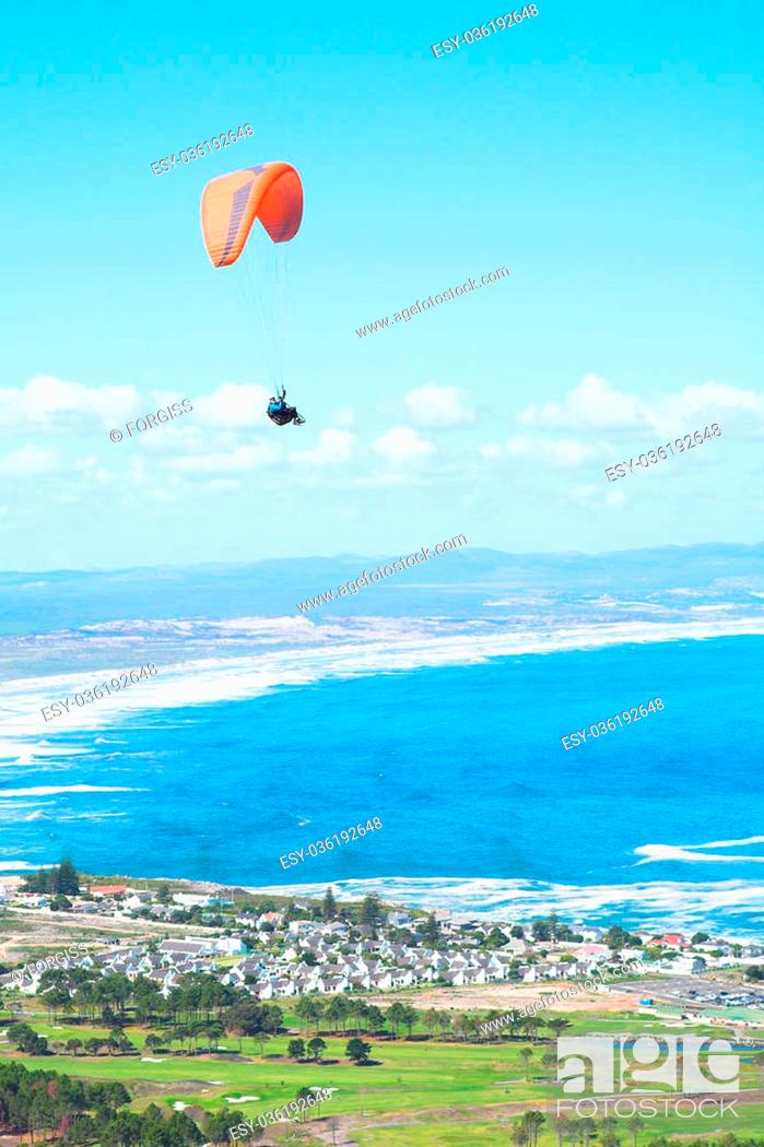 Stock Photo: Paraglider launching from the ridge with a yellow and white canopy. The shot is taken right after takeoff. The canopy wingtip is sharp.
