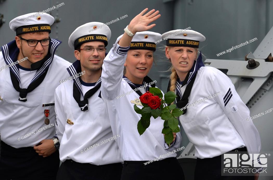 Stock Photo: A crew member of the frigate Augsburg waves as she stands between her comrades during the return of the frigate to the naval base in Wilhelmshaven, Germany.