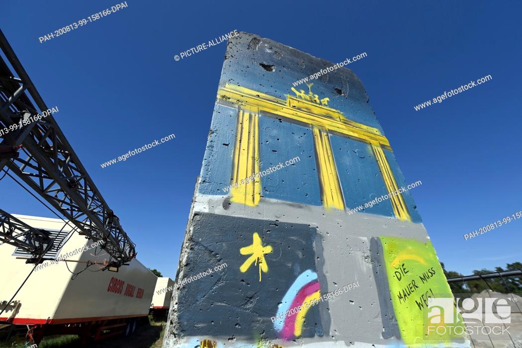 Stock Photo: 12 August 2020, Brandenburg, Teltow: Painted and sprayed with paint parts of the Berlin Wall stand on an industrial site near the harbour basin on the Teltow.