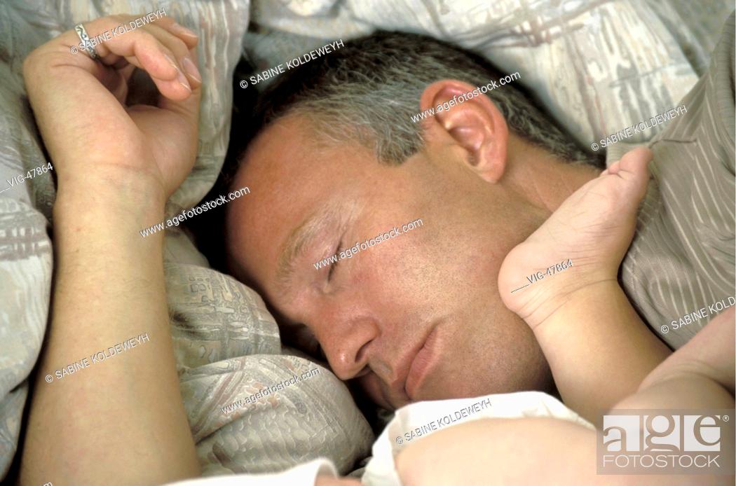 Stock Photo: Sleeping men with feets of a baby in his face. - ERKELENZ, GERMANY, 04/11/2003.
