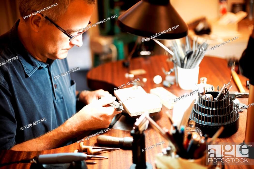 Stock Photo: Senior jeweler sitting and working at his table.