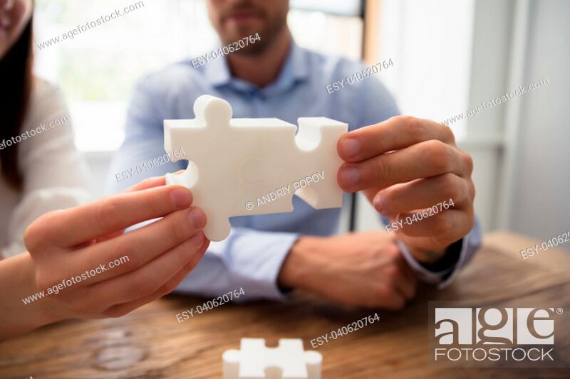 Stock Photo: Close-up Of Two Businesspeople White Jigsaw Pieces Over Wooden Desk.