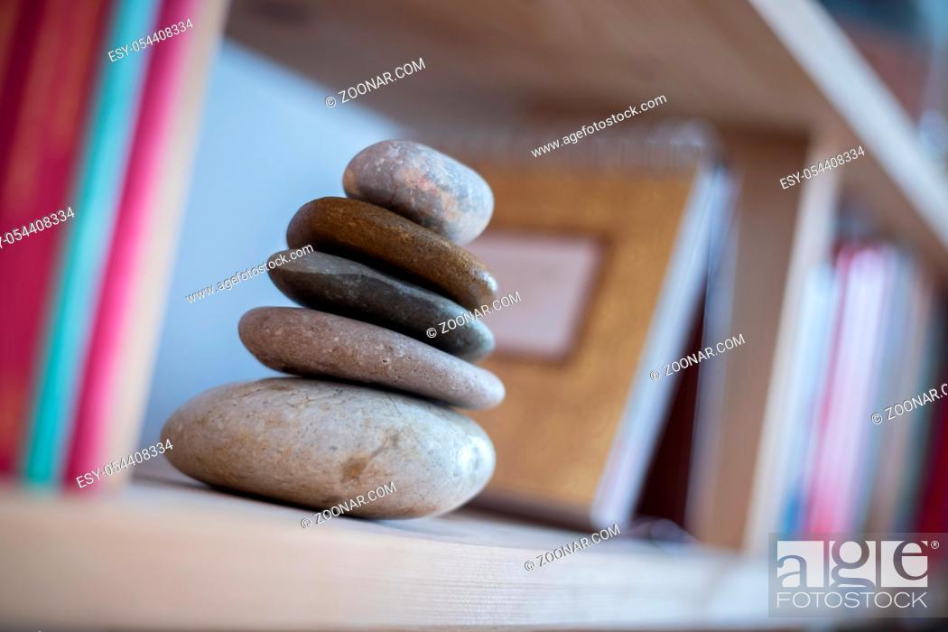 Stock Photo: Feng Shui: Stone cairn at home in a book shelf, blurry books in foreground and background. Balance and relaxation.