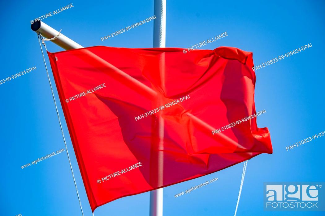 Stock Photo: 23 August 2021, Mecklenburg-Western Pomerania, Binz: On the Baltic Sea beach, a red flag on the DLRG tower signals that ""swimming and bathing is prohibited"".