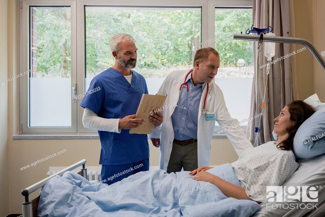 Stock Photo: Doctors making rounds, talking with patient in hospital room.