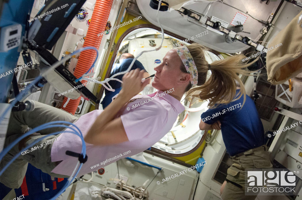 Stock Photo: NASA astronaut Karen Nyberg, Expedition 36 flight engineer, speaks into a microphone in the International Space Station's Quest airlock while the crew prepares.