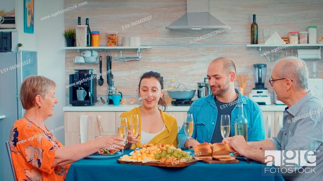 Stock Photo: Happy family celebrating birthday enjoying time together making cheers with white wine. Multi generation, four people, two happy couples talking and eating.