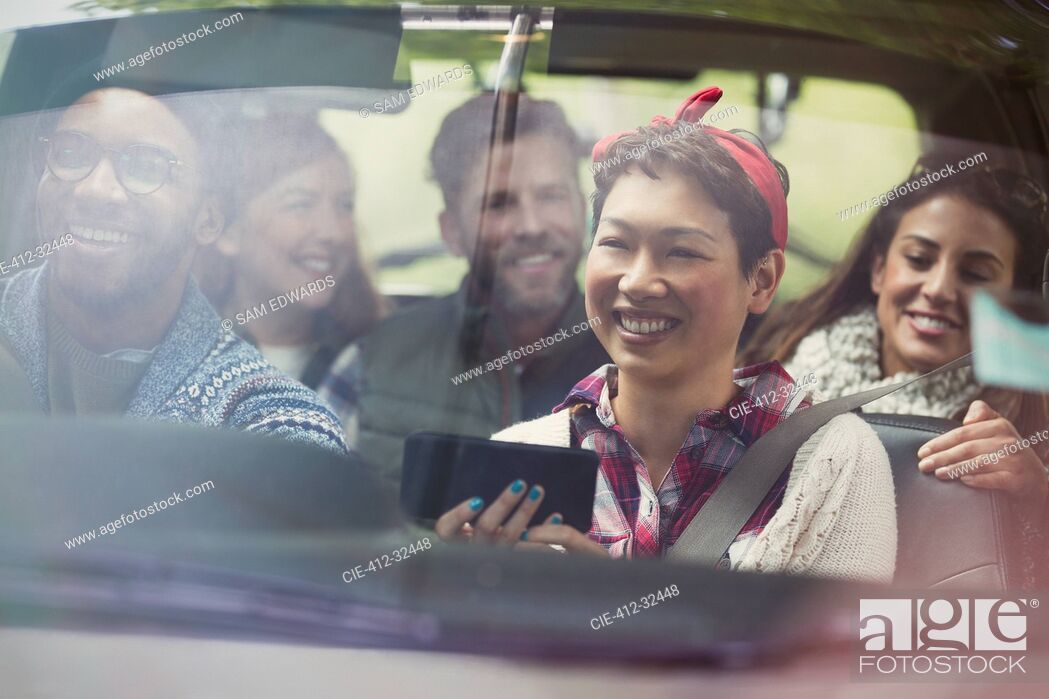 Stock Photo: Smiling friends using GPS on smart phone riding in car.