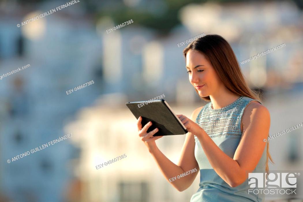 Stock Photo: Serious woman uses a tablet in a town outskirts at sunset.