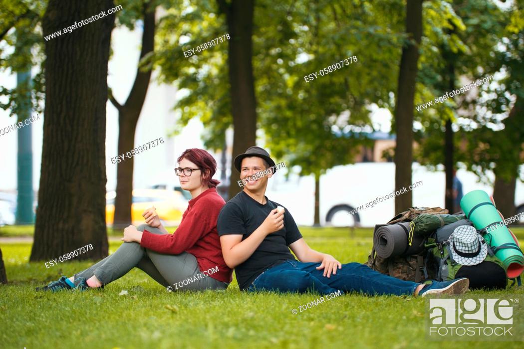 Stock Photo: Teenagers tourists with backpacks are eating the icecream in the park, telephoto shot.