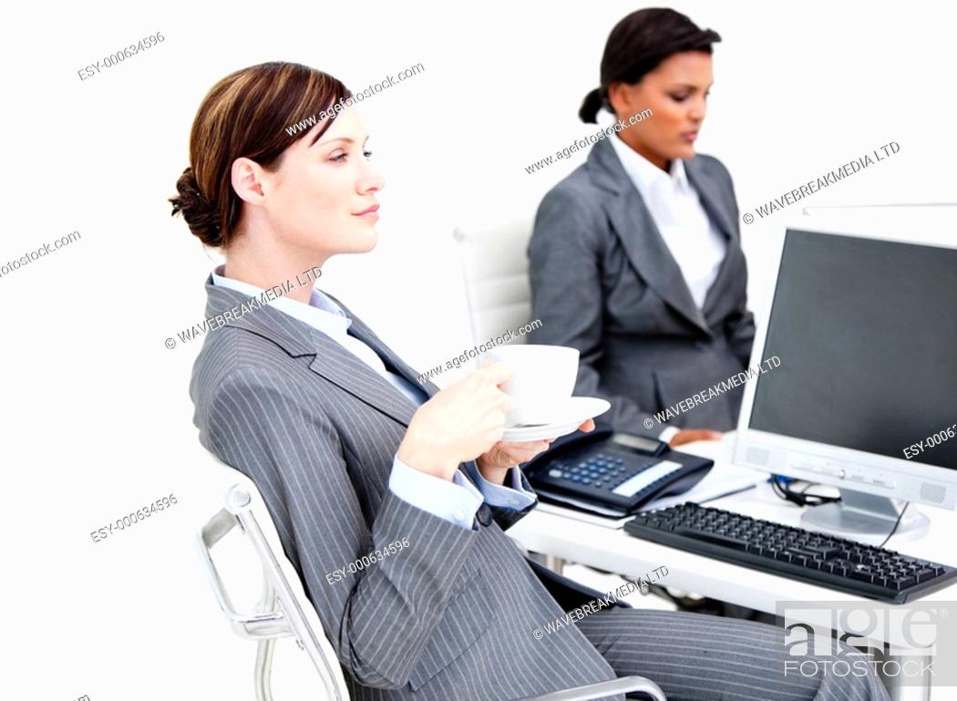 Stock Photo: Busy female business partners drinking coffee while having a break in the office.
