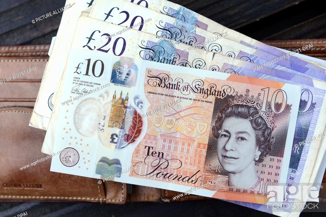 Stock Photo: 09 July 2019, Great Britain, St Ives: British pound lying on a wallet in St. Ives. Photo: Hendrik Schmidt/dpa-Zentralbild/ZB.