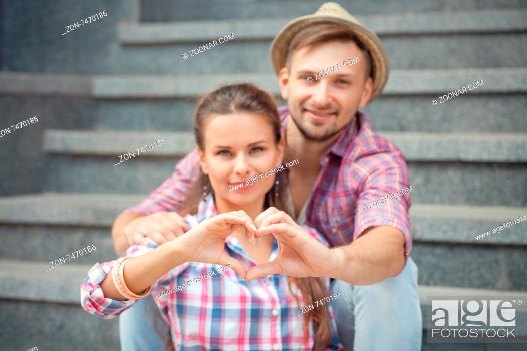 Stock Photo: Portrait of young smiling people embracing tenderly and bonding. Man and woman making heart with their hands.