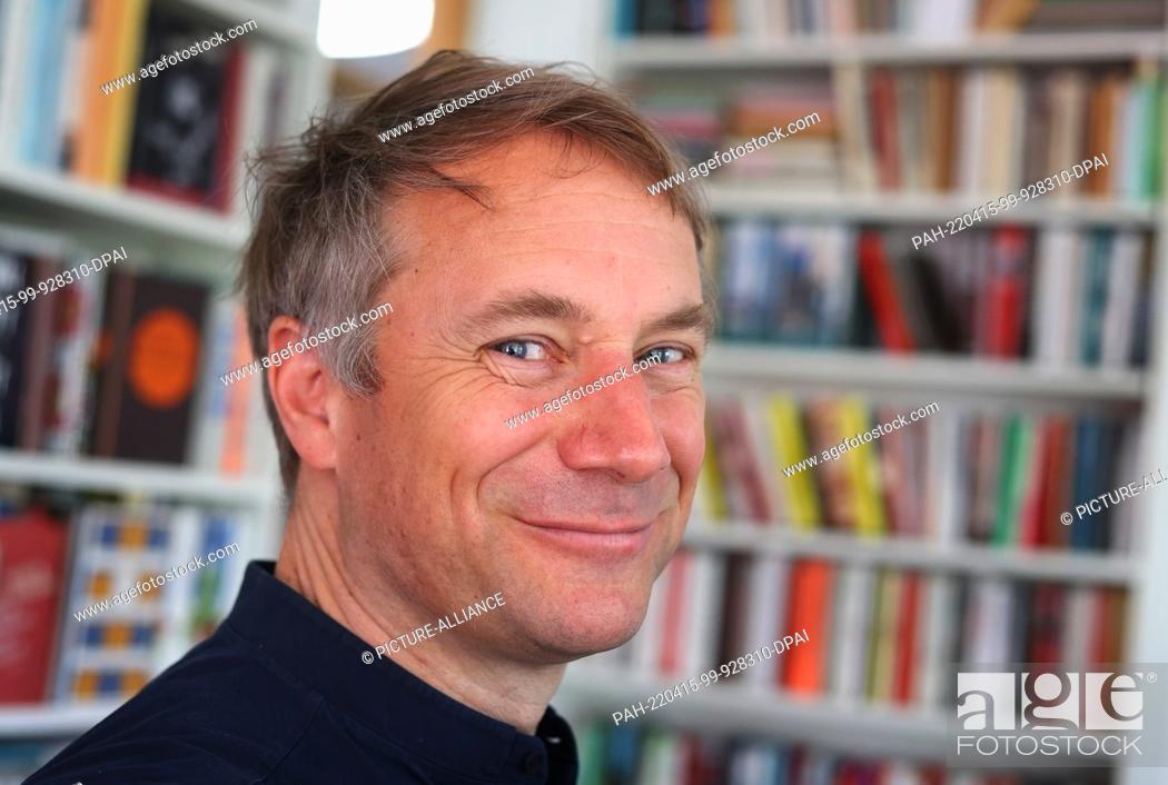 Stock Photo: 14 April 2022, Bavaria, Munich: Jo Lendle, writer and publisher of Carl Hanser Verlag, stands in front of books in his office.