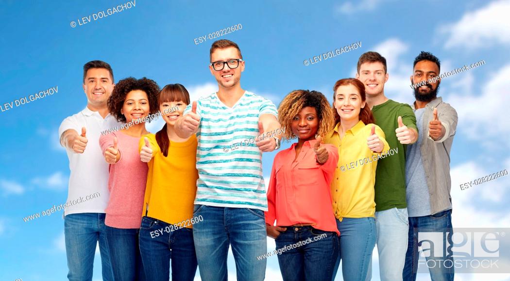 Photo de stock: diversity, race, ethnicity and people concept - international group of happy smiling men and women showing thumbs up over blue sky and clouds background.
