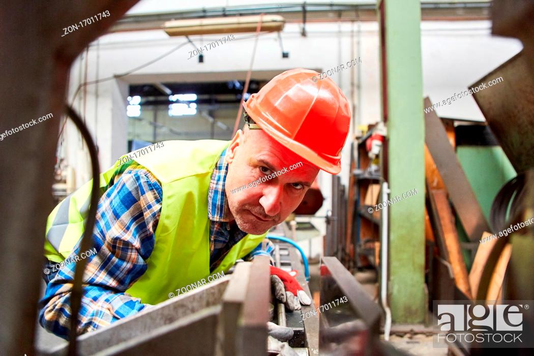 Stock Photo: Arbeiter mit Schutzhelm arbeitet an einer Maschine in der Schlosserei in der Metallfabrik.