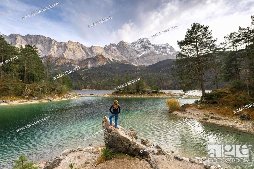 Stock Photo: Young woman standing on a rock on the shore, view into the distance, Eibsee lake in front of Zugspitzmassiv with Zugspitze, Wetterstein range, near Grainau.