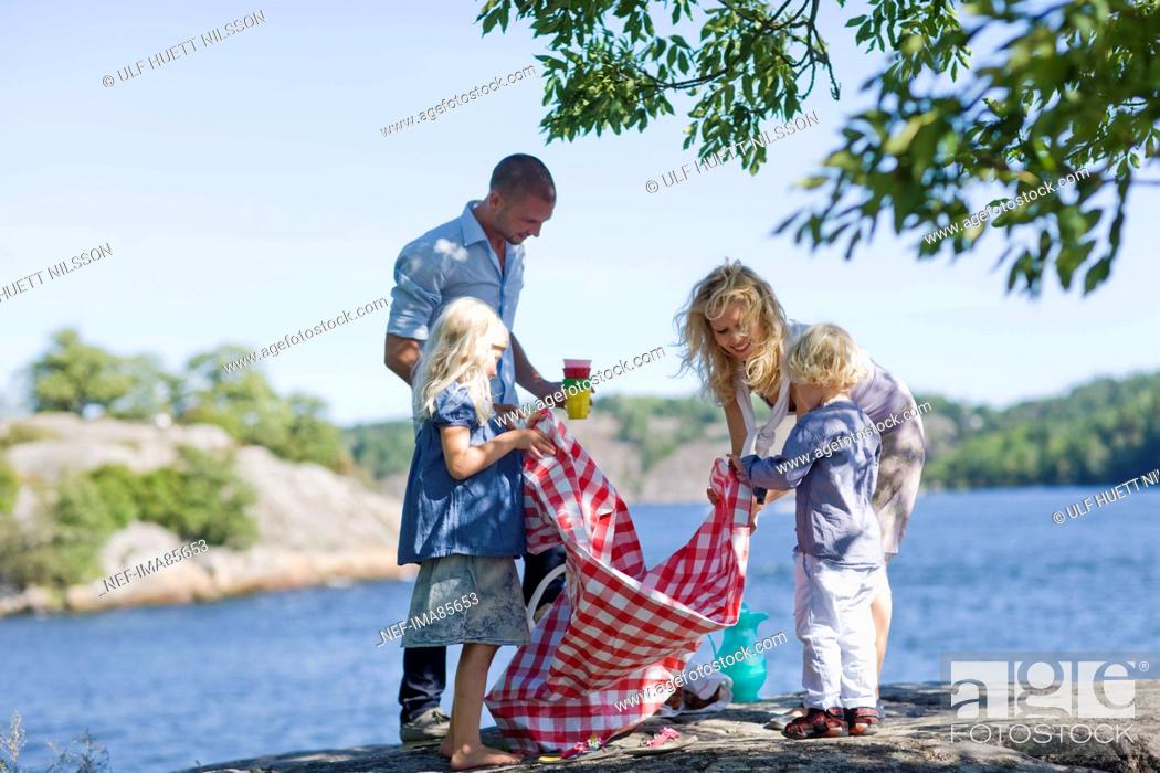 Stock Photo: Family preparing for picnic beside lake.