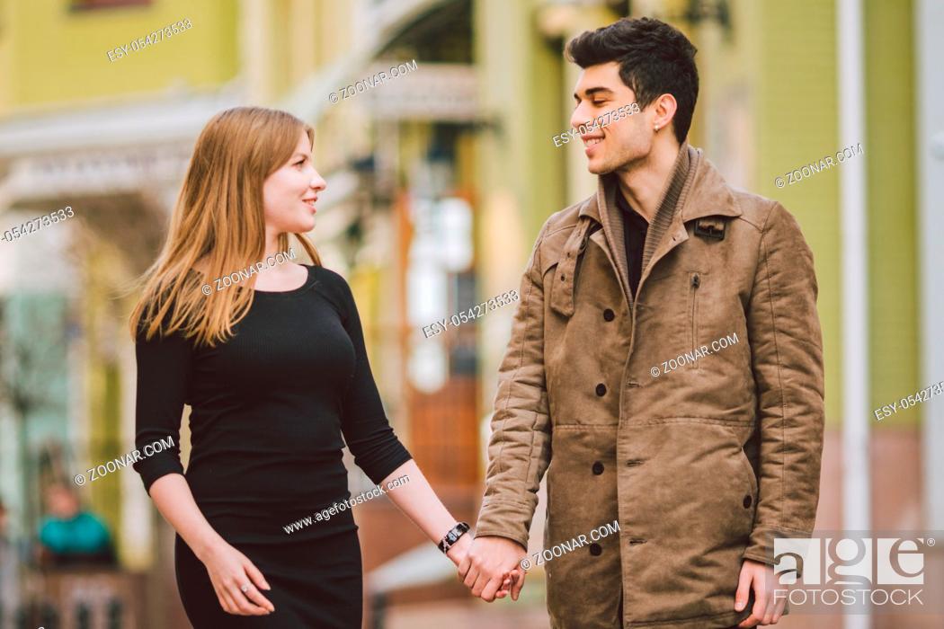 Stock Photo: Urban modern young love couple walking romantic talking talking, holding hands on a date. Young multicultural Turkish brunette and Caucasian couple on old.