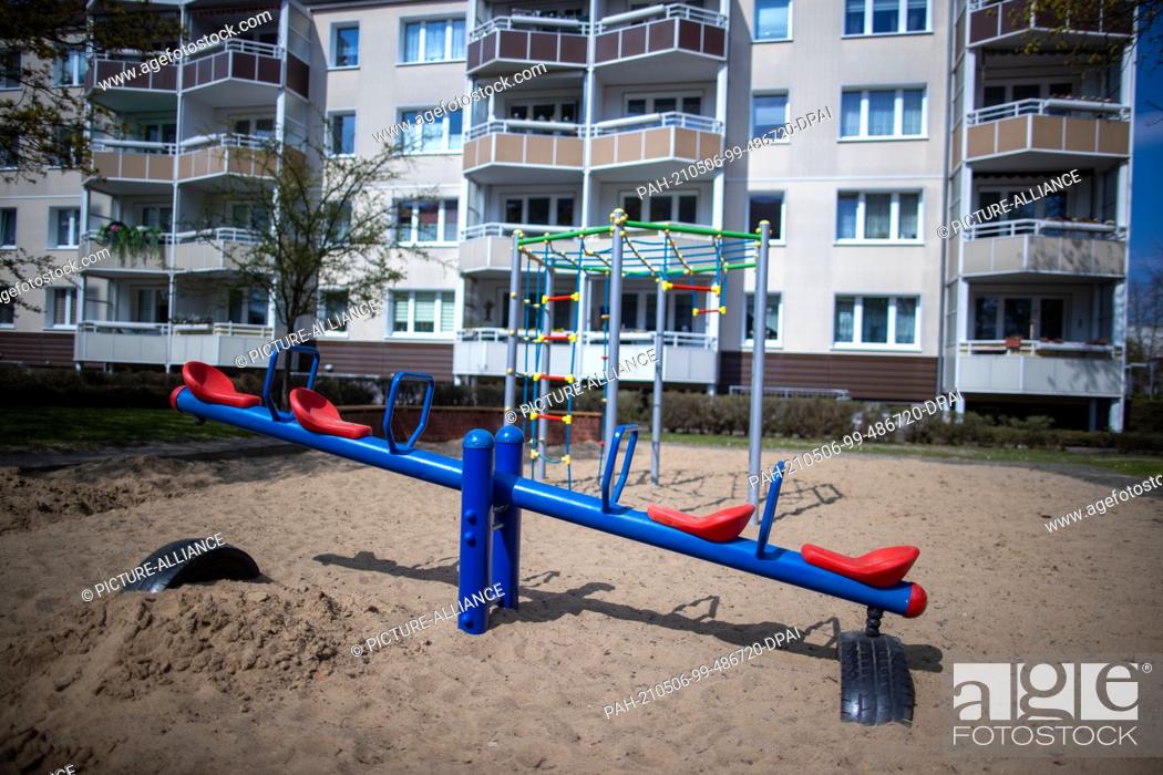 Stock Photo: 28 April 2021, Mecklenburg-Western Pomerania, Pasewalk: An empty seesaw on the children's playground in front of a new apartment block on Marktstraße.