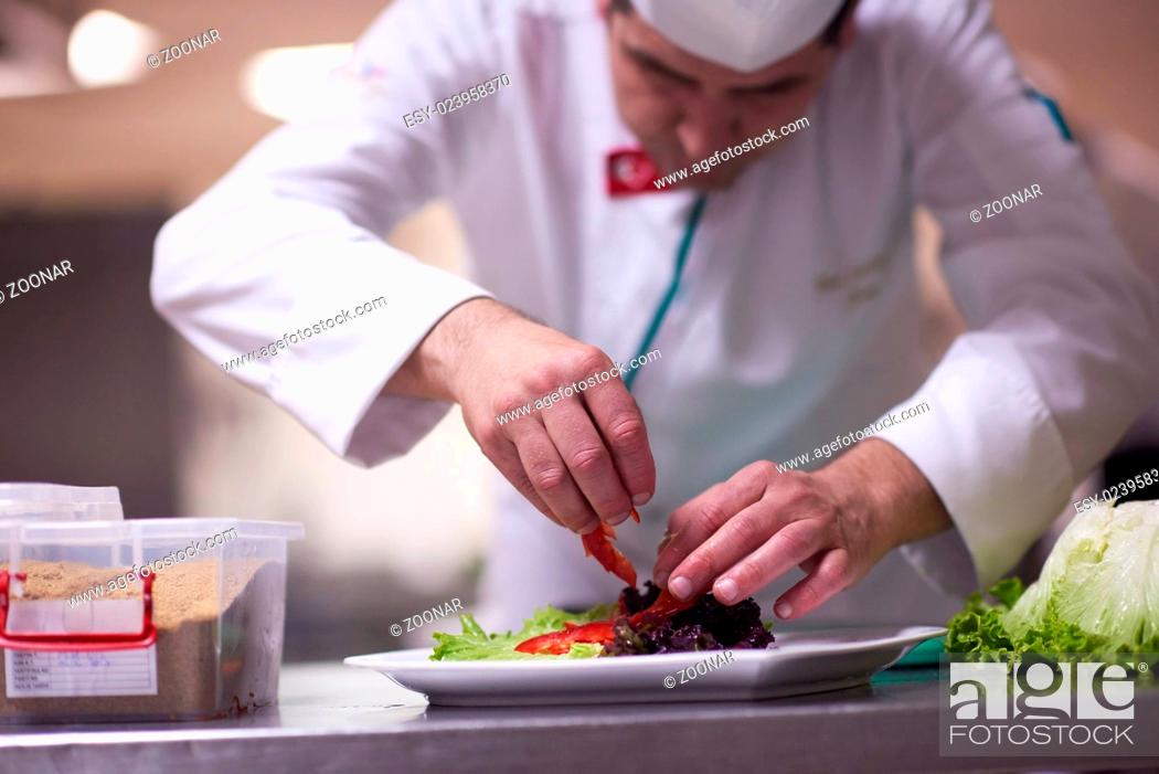 Stock Photo: chef in hotel kitchen preparing and decorating food.