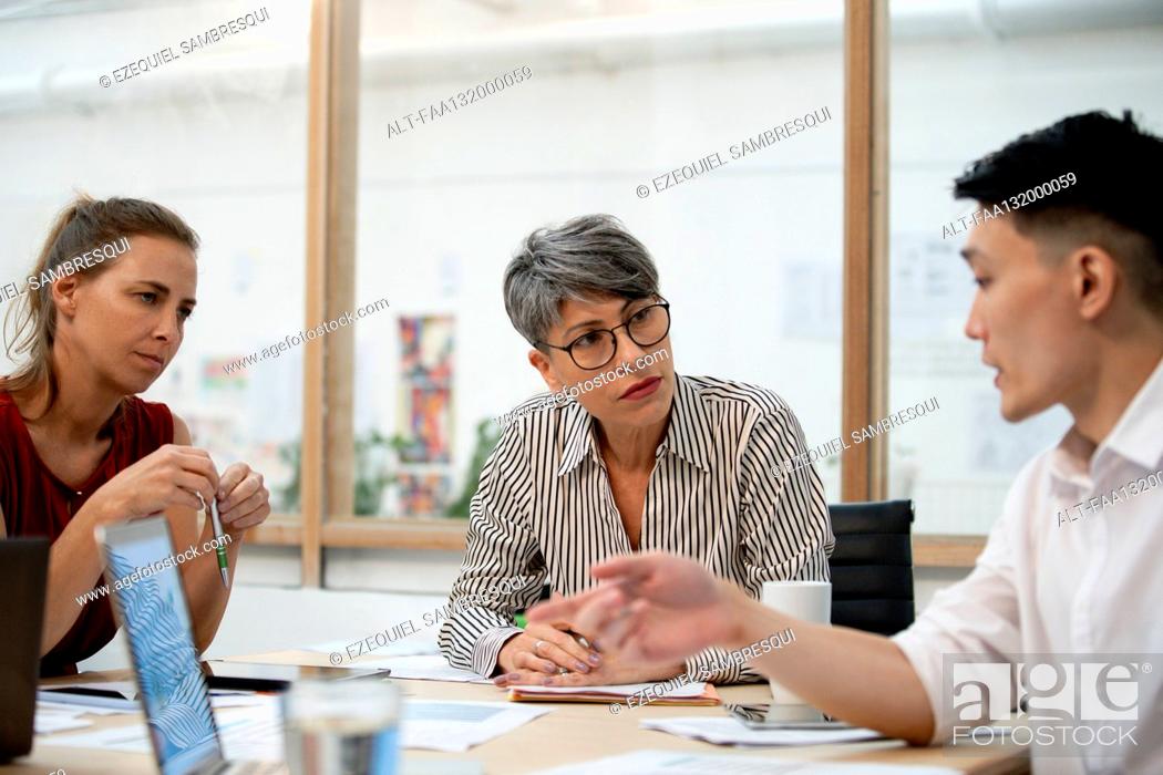 Photo de stock: Businesswoman listening to coworkers during project meeting.
