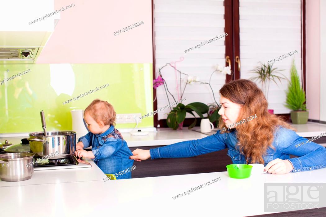 Stock Photo: Mom closely follows her son in the kitchen.