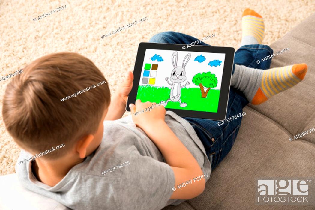 Stock Photo: High Angle View Of Cute Little Child Playing Game On Digital Tablet.