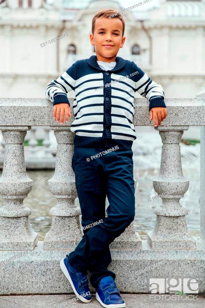 Stock Photo: Stylish rich little boy in fashionable clothes . Leaned on Granite-stone handrails. stylish, handsome posing outside in the city park.