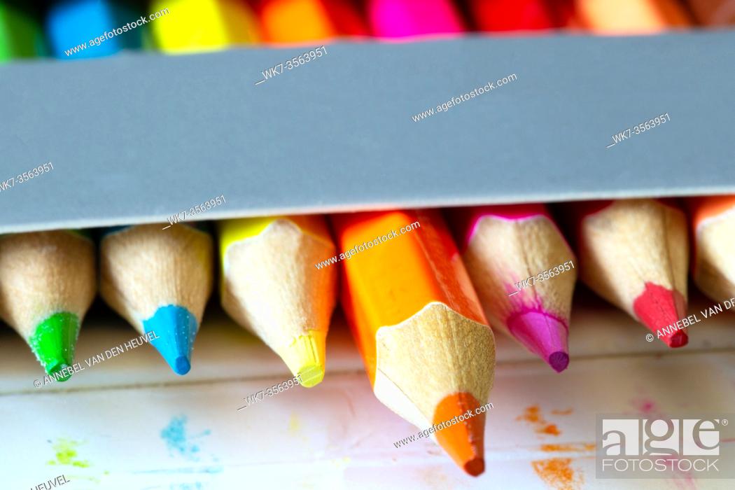 Stock Photo: Colored pencils in a carton grey box, rainbow colors, orange pencil sticks out macro, school or office supplies background.