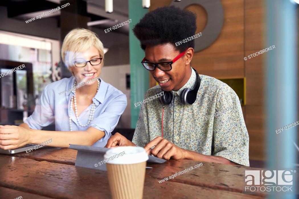 Stock Photo: Two Young Businesspeople Working On Laptop In Coffee Shop.