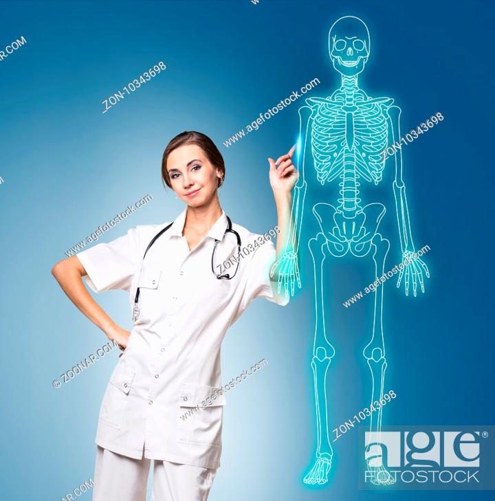 Stock Photo: Medical doctor woman pointing on drawing human skeleton, over blue background.