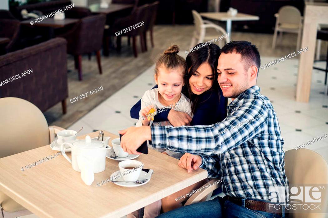 Stock Photo: family, parenthood, technology and people concept - happy mother, father and little girl having dinner and taking selfie by smartphone at restaurant.