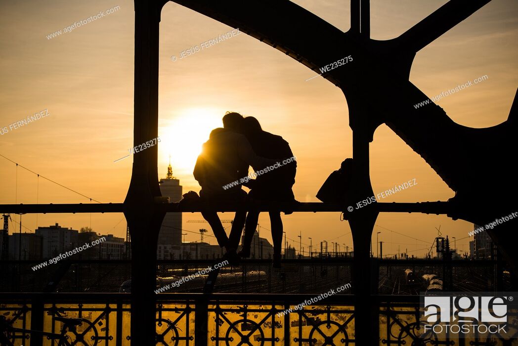 Stock Photo: Munich, Germany, March 23, 2017: A couple watches the sunset from a bridge over the railroad tracks.