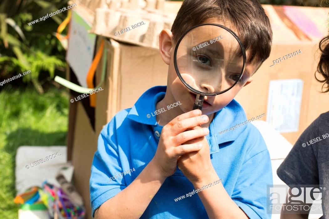 Stock Photo: Portrait of cute boy with magnifying glass in back yard.