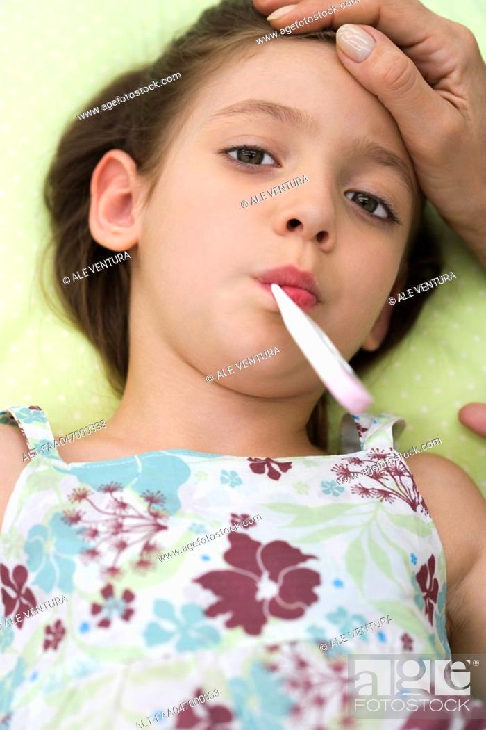 Stock Photo: Little girl lying down with thermometer in mouth.
