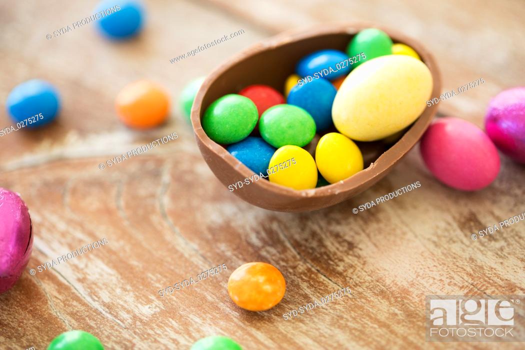 Stock Photo: chocolate easter egg and candy drops on table.