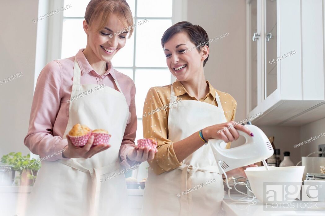 Stock Photo: Smiling female caterers baking muffins in kitchen.