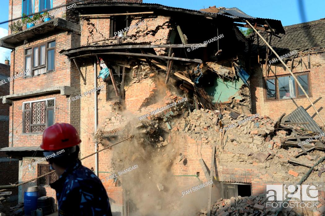 Stock Photo: A Nepalese police officer watches the demolition work of a damaged house in Bungmati, Nepal, 05 May 2015. | usage worldwide. - Bungmati/Nepal.