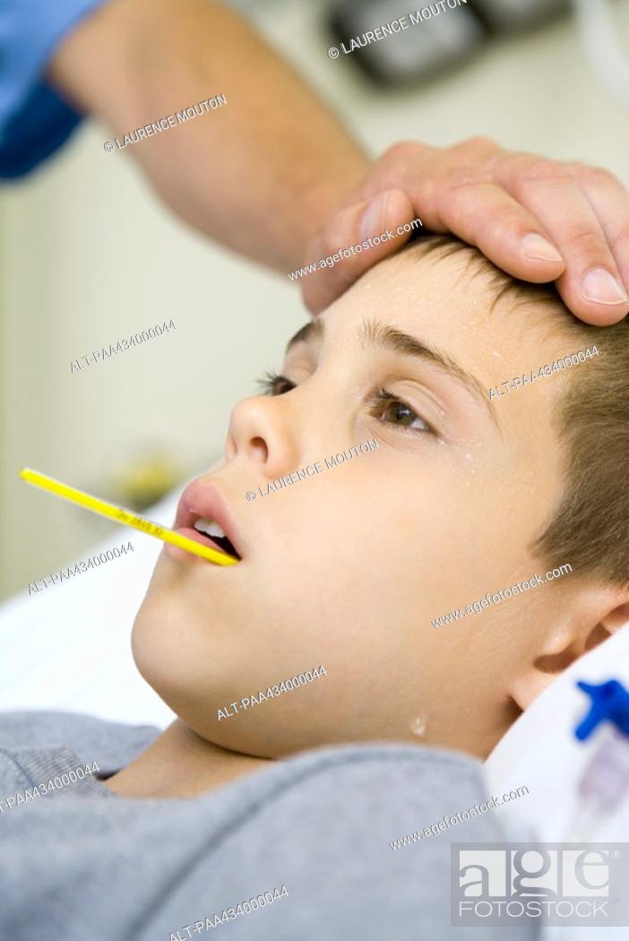 Stock Photo: Boy with thermometer in mouth and man's hand on forehead.