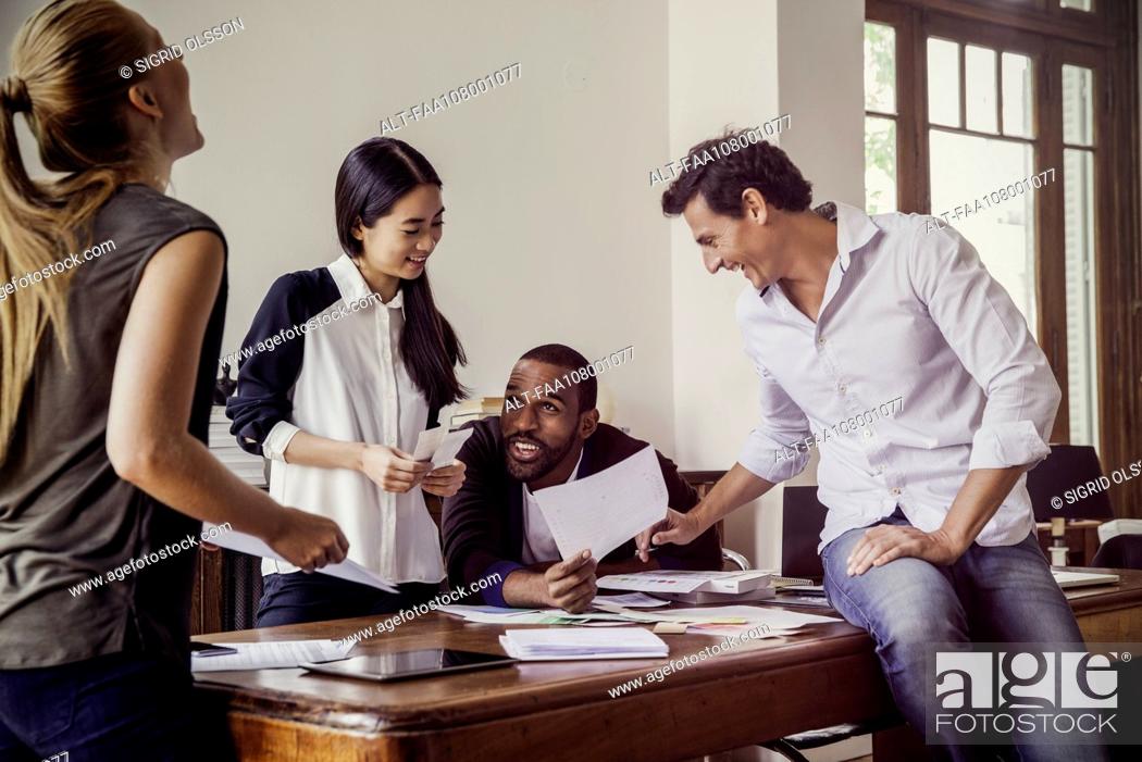 Stock Photo: Colleagues laughing together while collaborating on project.