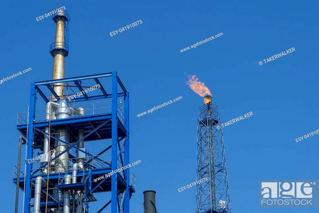 Stock Photo: Gas flares in petroleum refinery with blue sky background.