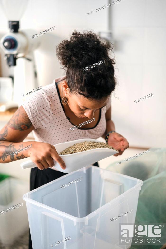 Stock Photo: Woman working in a coffee roastery examining coffee beans.