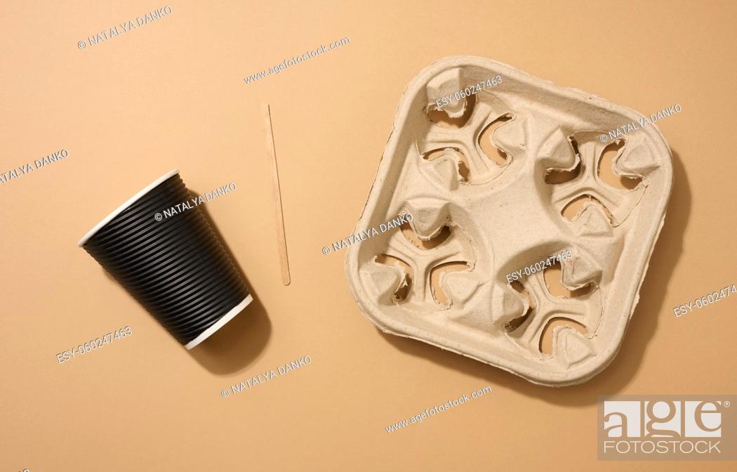 Stock Photo: brown disposable corrugated cardboard cup, wooden stirring stick and holder on brown background. View from above.