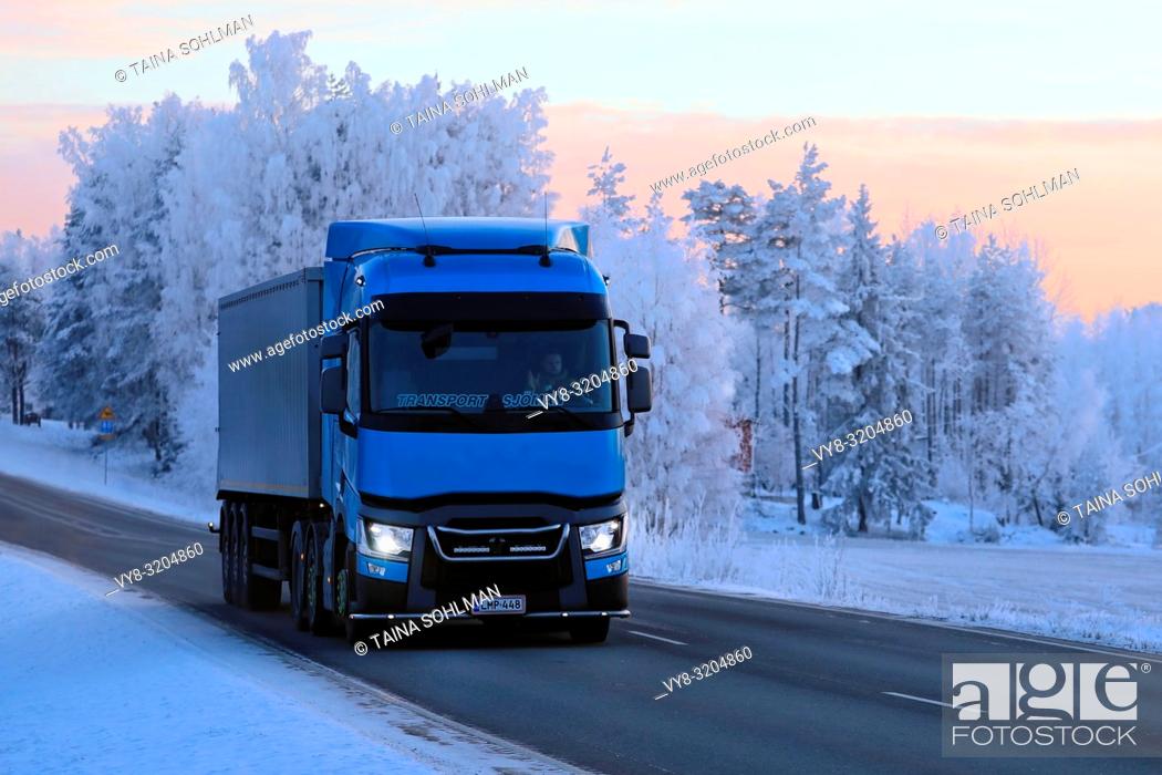 Stock Photo: Salo, Finland - January 19, 2018: Blue Renault Trucks T semi of Transport Sjoman Oy Ab pulls trailer on rural highway through winter scenery at dusk.